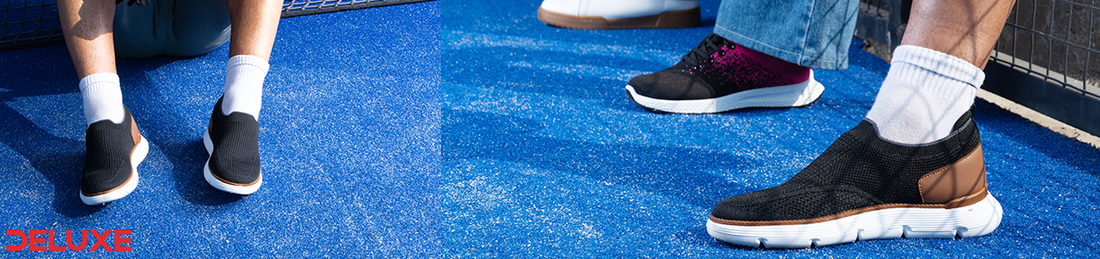 Person wearing Deluxe black breathable slip-on sneakers with cushioned white sole and white socks on a blue sports court, ideal for everyday walking and casual wear