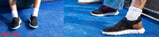 Person wearing Deluxe black breathable slip-on sneakers with cushioned white sole and white socks on a blue sports court, ideal for everyday walking and casual wear